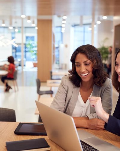 two-businesswomen-with-laptop-at-desk-in-open-UA7ST9U.min_.jpg